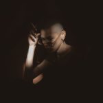 light and shadow photo of woman in dark room holding a cigarette