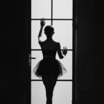 unrecognizable ballerina touching door in darkness